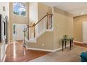 Bright foyer featuring hardwood floors, staircase with wood banister, and large arched window above doorway at 4114 Suwanee Trail Dr, Buford, GA 30518