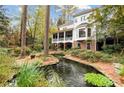 Secluded backyard featuring a covered porch, lush landscaping, brick accents, and tranquil creek water feature at 769 Hampton Sw Pl, Marietta, GA 30064