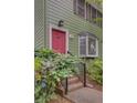Two-story home with a bright pink door, green siding, and brick steps at 6 Holly Downs Nw Ct, Atlanta, GA 30318