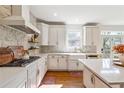 Bright kitchen featuring white cabinets, stainless steel appliances, and natural stone backsplash at 6640 Stratford Pl, Cumming, GA 30040