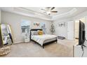 Spacious bedroom featuring a tray ceiling, soft carpet, and an ensuite bathroom at 5575 Rock Place Ct, Norcross, GA 30093