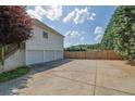 Spacious three-car garage with ample parking on a concrete driveway, framed by a privacy fence and mature evergreens at 6455 Crystal Ln, Cumming, GA 30040