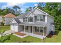 Traditional two-story home with an inviting front porch, two-car garage, and mature trees surrounding the property at 6895 Smoke Ridge Dr, Atlanta, GA 30349