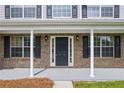 Close-up of the brick front porch, showcasing the entrance door, white columns, and classic exterior lighting at 6895 Smoke Ridge Dr, Atlanta, GA 30349