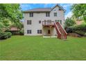 Expansive backyard featuring lush green lawn, mature trees, and wooden stairs leading to a deck at 5435 Vicarage Walk, Alpharetta, GA 30005