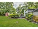 Lush backyard featuring a green lawn, mature trees, a pool and deck with an outdoor shed at 1615 Arden Sw Dr, Marietta, GA 30008