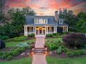 Charming home features lush landscaping, a brick walkway, and a welcoming covered porch at 11660 Crabapple Rd, Roswell, GA 30075