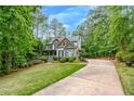 Exterior view of two-story home with lush landscaping and a long driveway to the side of the house at 529 Wintergreen Way, Canton, GA 30115