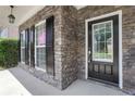 Inviting front porch with stone accents, black shutters, and a glass-paneled front door at 3208 Juniper Nw Dr, Kennesaw, GA 30144