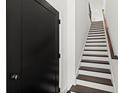 Staircase with dark wood treads and white risers, next to a sleek black door at 2335 Mason Dr # D27, Atlanta, GA 30316