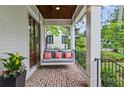 Relaxing front porch featuring a swing, brick flooring, and views of the landscaped yard at 686 Amsterdam Ne Ave, Atlanta, GA 30306