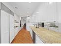 Galley kitchen featuring white cabinets, granite countertops, and modern appliances at 2660 Peachtree Rd # 7F, Atlanta, GA 30305