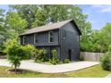 Modern two-story home featuring dark siding, manicured lawn, concrete driveway and green landscaping at 2824 Tupelo Se St, Atlanta, GA 30317