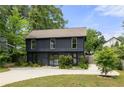 Stylish two-story home with dark siding, green lawn and a paved driveway surrounded by lush trees at 2824 Tupelo Se St, Atlanta, GA 30317