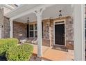 Inviting front porch with decorative stone, seating, hanging lanterns and an elegant front door at 485 St Annes Pl, Covington, GA 30016