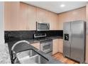 Modern kitchen featuring stainless steel appliances, dark backsplash, granite countertops, and wood cabinetry at 860 Peachtree Ne St # 909, Atlanta, GA 30308
