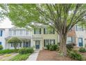 Charming townhome with light yellow siding, dark blue shutters, front yard foliage, and a mature shade tree at 3746 Berkeley Xing, Duluth, GA 30096