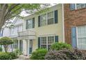 Well-maintained townhome with light yellow siding, dark blue shutters, and manicured front yard landscaping at 3746 Berkeley Xing, Duluth, GA 30096