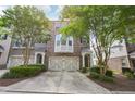 Charming brick townhome with a two-car garage, covered entrance, and lush landscaping creating a welcoming curb appeal at 6080 Indian Wood Se Cir, Mableton, GA 30126