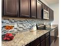 Modern kitchen featuring granite countertops, dark wood cabinets, and stainless steel appliances at 3785 Newbury Place Dr, Loganville, GA 30052