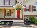 Inviting covered front porch with wood columns and a bright red front door at 405 Maple Rdg, White, GA 30184