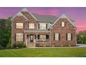Stunning brick home with black shutters and a well-manicured lawn at dusk at 6375 Haystack Ct, Cumming, GA 30040