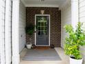 Inviting front porch area, enhanced by a rug, potted plants, and brick details at 302 Braswell Ct, Woodstock, GA 30188