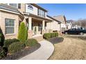 Inviting two-story home showcasing brick facade, manicured lawn, and a charming covered front porch with decorative columns at 6280 Stillwood Ln, Cumming, GA 30041