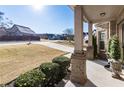 Charming front porch featuring brick columns, manicured bushes, and a view of the home's expansive front yard at 6280 Stillwood Ln, Cumming, GA 30041