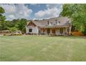 A picturesque two-story home with a spacious lawn and welcoming covered porch with wooden pillars at 1142 Wiley Bridge Rd, Woodstock, GA 30188