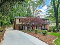 View of a two-story brick home with driveway, well-manicured landscaping, and mature trees at 2151 Desmond Dr, Decatur, GA 30033