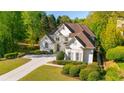 Beautiful white two-story home with manicured landscaping and a concrete driveway at 5685 Commons Ln, Alpharetta, GA 30005