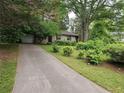 A long concrete driveway leads up to a single-story brick home with lush landscaping and mature trees at 1517 Colony East Cir, Stone Mountain, GA 30083