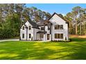 Stylish two-story home boasts black frame windows, white brick, dark roof, and a lush lawn at 400 Auburn Rd, Auburn, GA 30011