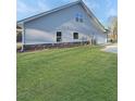 Side of a home with grey siding, stone accents, and a well manicured lawn at 5331 Tuscany Dr, Douglasville, GA 30135