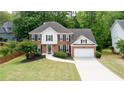Aerial view of a well-manicured two-story home with a two-car garage and mature landscaping at 1812 Riverton Dr, Suwanee, GA 30024