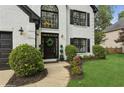 Inviting home entrance with a black door, lovely landscaping, and decorative black outdoor lights at 230 Bluff Oak Dr, Roswell, GA 30076