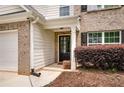 Inviting front entrance featuring brick accents, complemented by a covered porch, a black door and landscaped garden at 10204 Deep Creek Pl, Union City, GA 30291