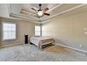 Spacious bedroom featuring a tray ceiling, ceiling fan, and natural light at 609 Grand Ashbury Ln, Buford, GA 30518