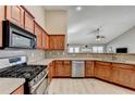 Modern kitchen features stainless steel appliances, wood cabinetry, and spacious countertops at 609 Grand Ashbury Ln, Buford, GA 30518
