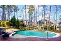 Inviting backyard pool with brick surround, surrounded by trees, offering a private and relaxing outdoor space at 93 Richmond Way, Villa Rica, GA 30180