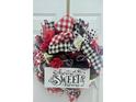 Festive 'Home Sweet Home' wreath with red, black, and white checkered ribbons and floral accents on the front door at 7491 Hilltop Way, Atlanta, GA 30349