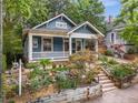 Inviting blue home with a covered porch, stone retaining wall, and beautiful landscaping at 165 Hale Ne St, Atlanta, GA 30307