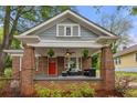 Inviting brick front porch with ample seating, stylish decor, and a vibrant red door at 540 Atwood Sw St, Atlanta, GA 30310