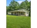 A view of the rear of a home with a sprawling green lawn and mature trees at 415 Gray Rd, Carrollton, GA 30116