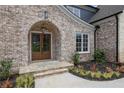 Inviting front entrance with a stylish brick archway and custom double doors at 5753 Brendlynn Dr, Suwanee, GA 30024