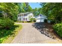 Charming two-story home with a well-manicured lawn, mature trees, and a brick driveway leading to an attached garage at 3605 Sewell Mill Rd, Marietta, GA 30062