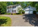 Beautiful two-story home with a manicured lawn and a brick driveway leading to an attached two-car garage at 3605 Sewell Mill Rd, Marietta, GA 30062