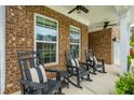 Covered front porch featuring rocking chairs and a brick facade, perfect for relaxing outdoors at 123 Woodford Ln, Canton, GA 30115