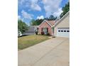Exterior view of a home with a well-manicured lawn and a paved driveway leading to the garage at 1150 Hillary Ln, Lawrenceville, GA 30043